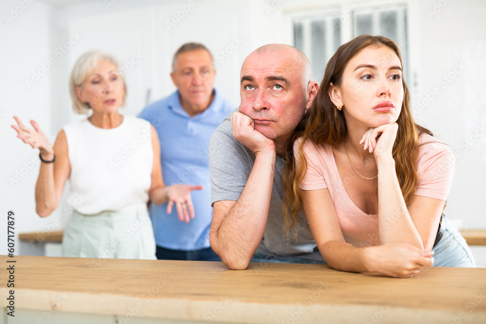 Fototapeta premium Husband and wife listen to their parents scold them in the home kitchen