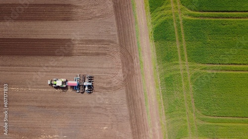 Tractor with a seed drill sowing on a field, aerial view, agriculture