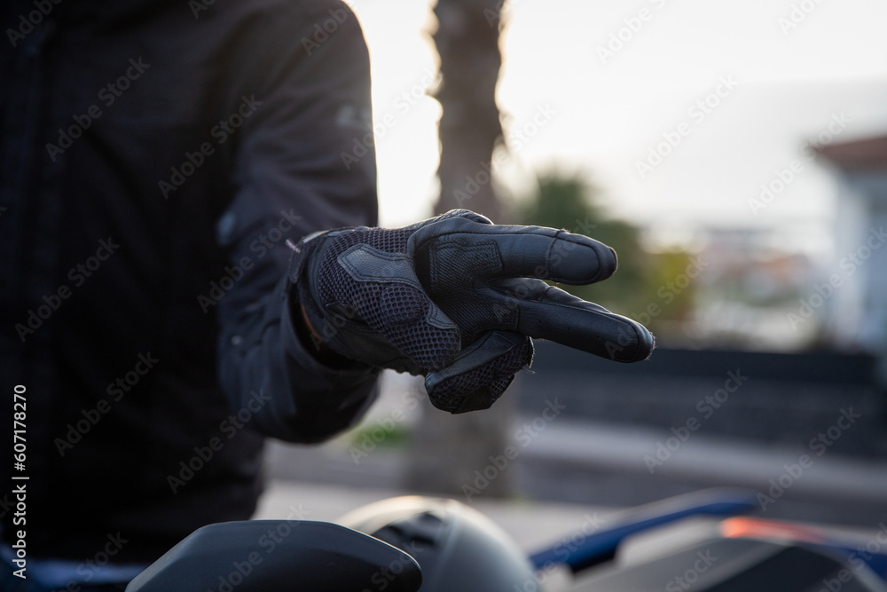 Close-up of a biker's hands showing the hand gestore of salute, the V gesture - obrazy, fototapety, plakaty 