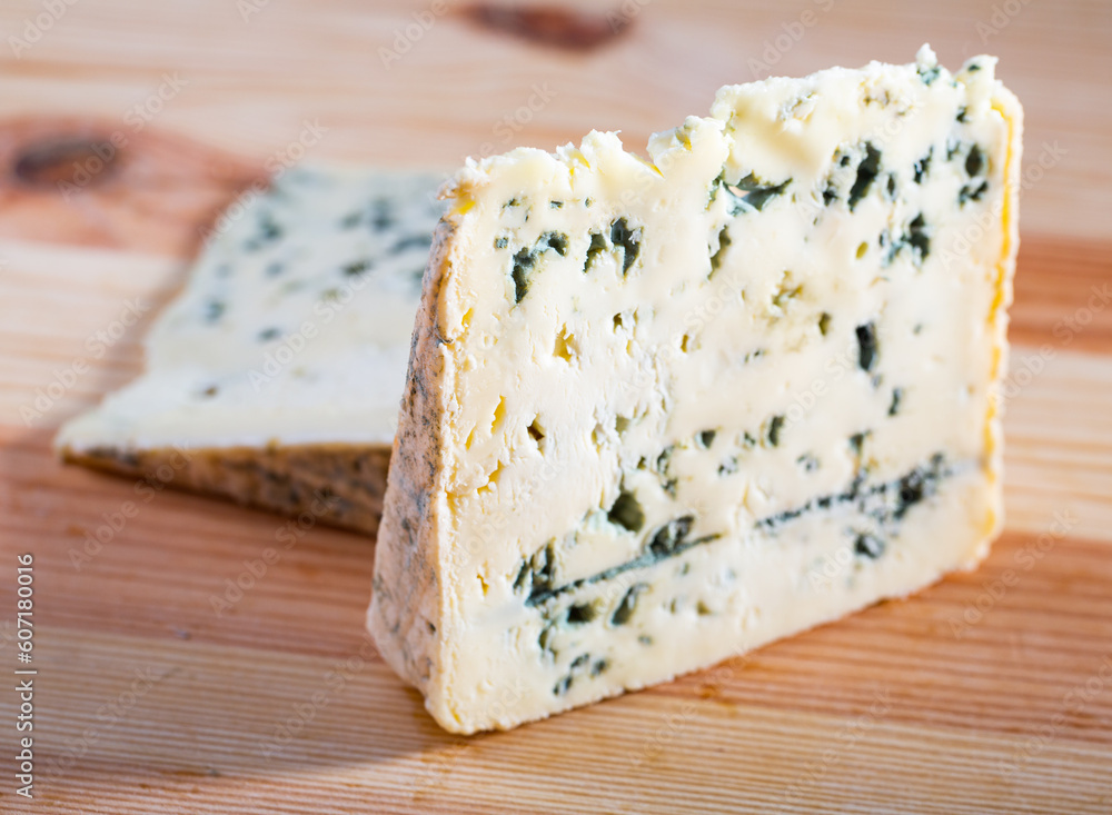 Slices of piquant soft blue cheese on wooden surface..