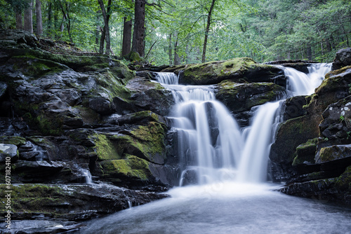 Waterfall flowing beautifully into creek river covered in moss long exposure silky smooth water in dark forest