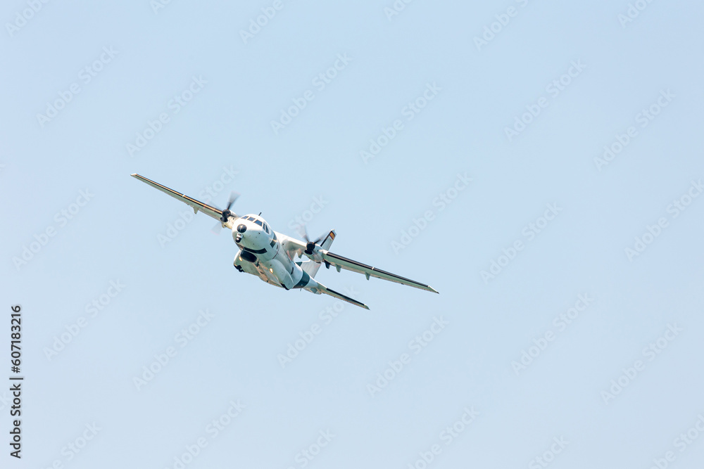 Close-up front view of a big white military cargo airplane flying over the blue sky at the Gijon air show festival Close-up front view of a big white military cargo airplane flying over the blue sky at the Gijon air show festival