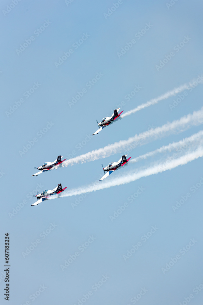 Planes squadron in arrow formation doing tricks and stunts over the blue sky with color wakes on a summer day at Gijon air show festival Planes squadron in arrow formation doing tricks and stunts over the blue sky with color wakes on a summer day at Gijon air show festival