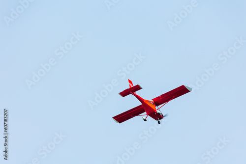 Bottom view of a red glider airplane flying and doing tricks over the blue air 