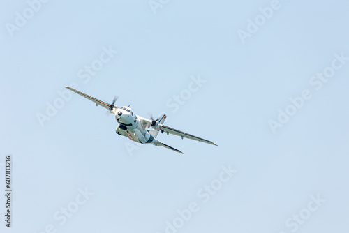 Close-up front view of a big white military cargo airplane flying over the blue sky at the Gijon air show festival