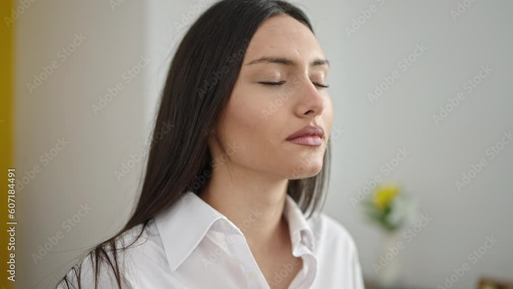 Young beautiful hispanic woman breathing with closed eyes at home