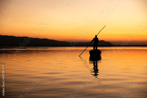 silhouette fisherman in boat at sunset