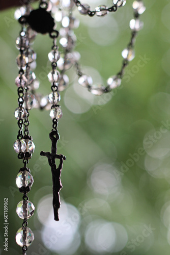 Crucifixo em cristal con fundo natural e iluminado, para oração. Objeto símbolo do cristianismo, que serve para rezar. Amuleto protetor e abençoaso. © angelafarina