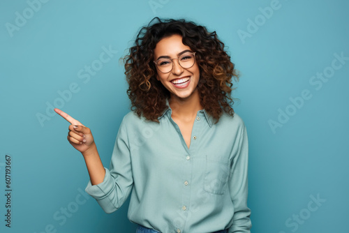 Obraz na płótnie Young woman pointing finger to side, smiling adult girl isolated on blue background,. Concept of business, person, show, beauty. w salonie
