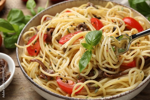 Delicious pasta with anchovies, tomatoes and spices on table, closeup