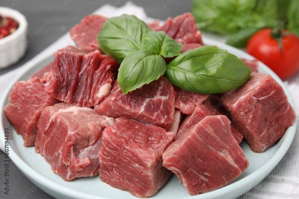 Cut fresh beef meat with basil leaves on table, closeup