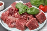 Cut fresh beef meat with basil leaves on table, closeup