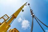 The hydraulic cylinders of an offshore oil rig crane are using four strong slings to lift large loads with four corner sling handles.