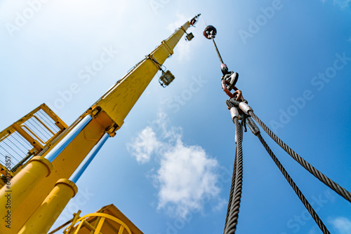 The hydraulic cylinders of an offshore oil rig crane are using four strong slings to lift large loads with four corner sling handles.