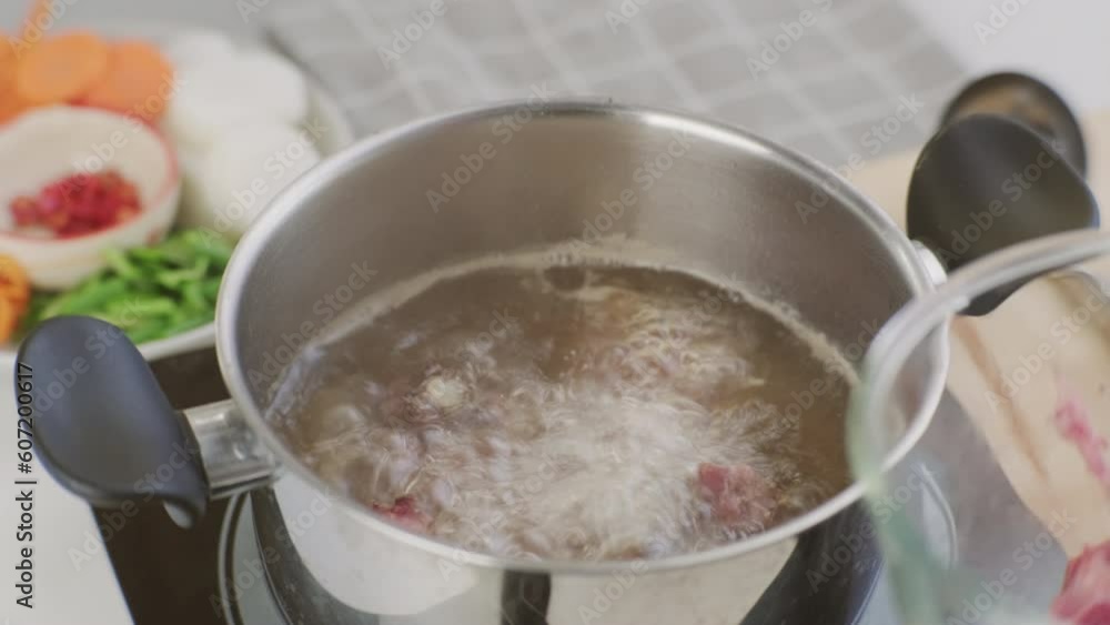 Cooking - Chef's hands are putting pork ribs in a pot of boiling water in the kitchen. Preparing pork stock with vegetables (broth) in a pot. Homemade bouillon recipe. Cooking - Chef's hands are putting pork ribs in a pot of boiling water in the kitchen. Preparing pork stock with vegetables (broth) in a pot. Homemade bouillon recipe.