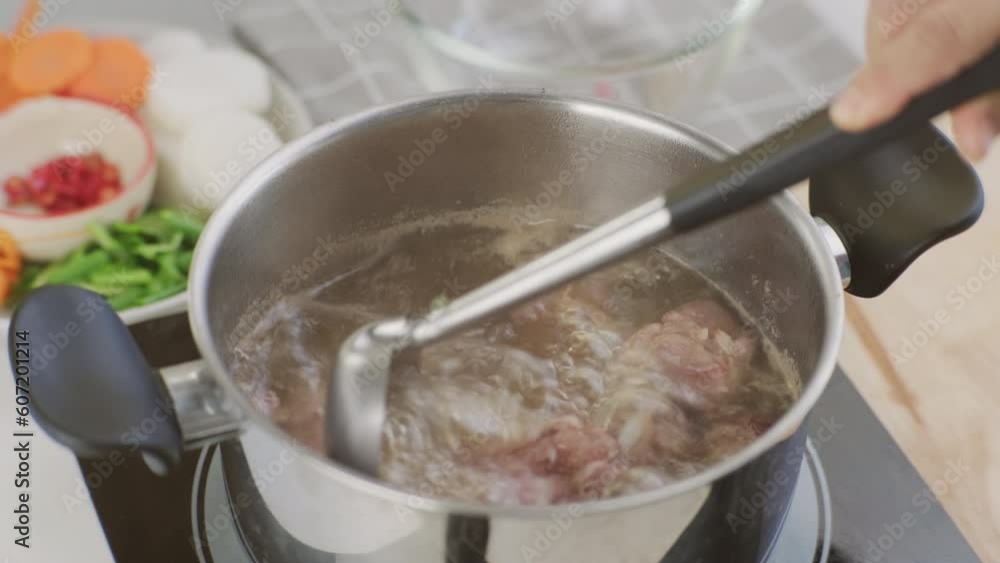 Cooking - Chef's hands are putting pork ribs in a pot of boiling water in the kitchen. Preparing pork stock with vegetables (broth) in a pot. Homemade bouillon recipe. Cooking - Chef's hands are putting pork ribs in a pot of boiling water in the kitchen. Preparing pork stock with vegetables (broth) in a pot. Homemade bouillon recipe.