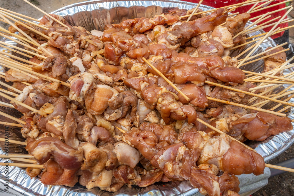 A large tray of filipino barbecue, marinated pork pushed onto skewers, ready to cook A large tray of filipino barbecue, marinated pork pushed onto skewers, ready to cook