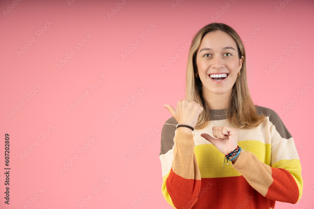 Happy young woman pointing with her thumb Happy young woman pointing with her thumb