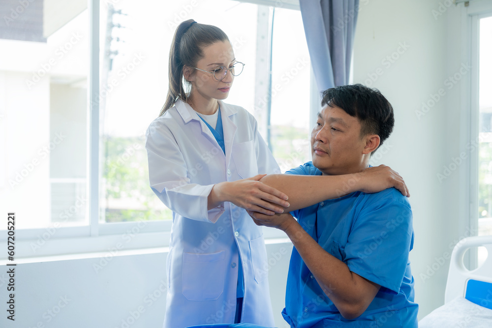 Obraz premium Female doctor's hand doing physiotherapy stretching the shoulder of a male patient. Doctor or physiotherapist working on male patient's limb muscle injury in clinic