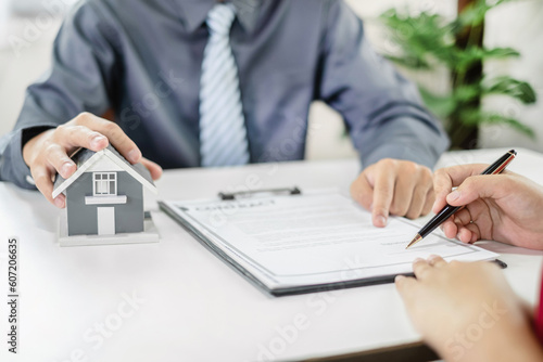 A real estate agent with a home model is talking to clients about renting a house and buying home insurance and contracting the contract after the formal negotiation is completed