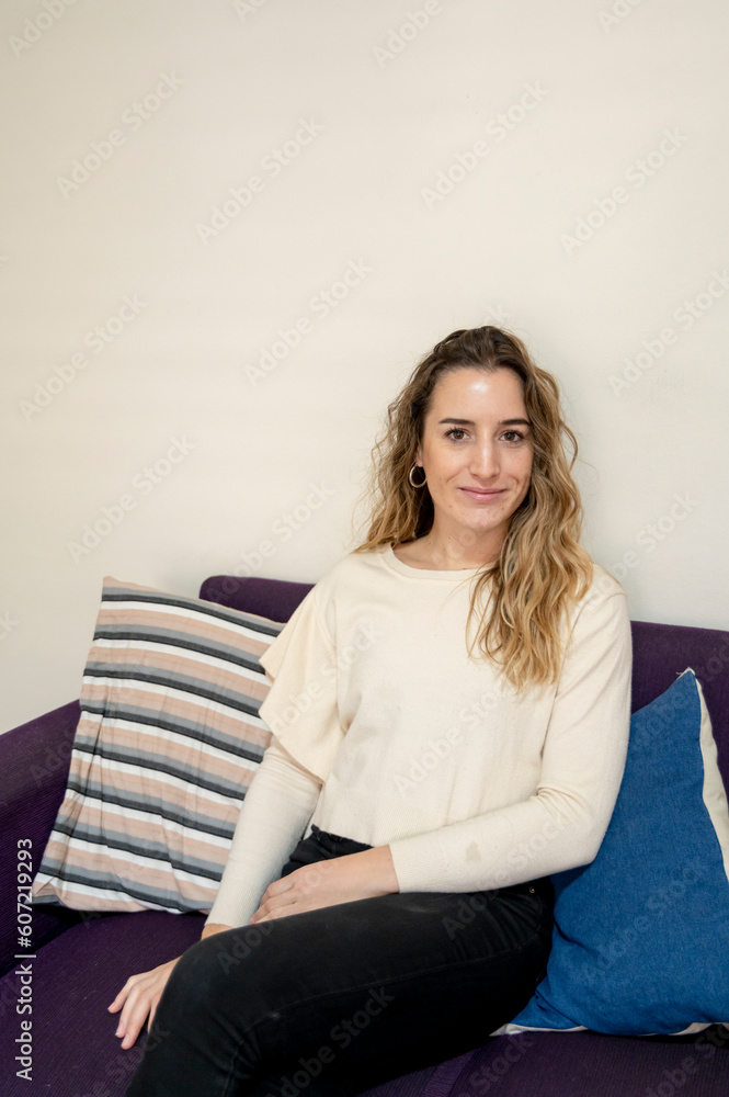 Woman smiling while sitting on a sofa at home. Woman smiling while sitting on a sofa at home.