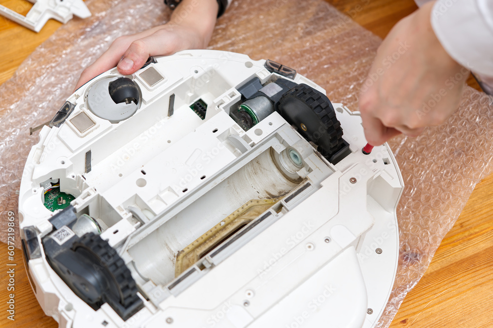 Serviceman, Repairman, maintenance on robotic vacuum cleaner. Repairing  robot cleaner. Electronics repair concept Stock Photo | Adobe Stock