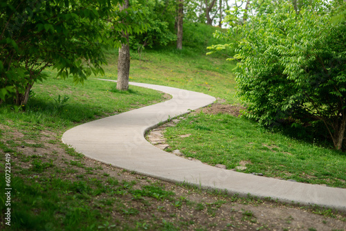 Fototapeta Naklejka Na Ścianę i Meble -  Winding walking concrete path in a summer park.