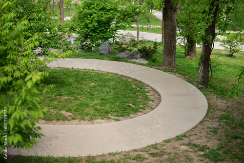 Winding walking concrete path in a summer park.