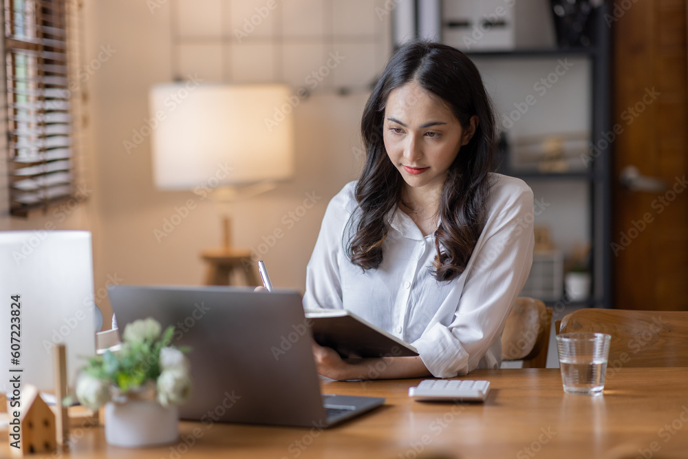Young adult happy smiling business asuan woman working on desk home office with using a calculator to calculate the numbers, finance accounting business educationconcept Young adult happy smiling business asuan woman working on desk home office with using a calculator to calculate the numbers, finance accounting business educationconcept