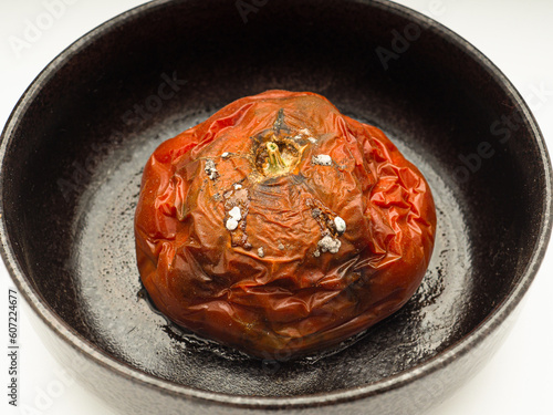 Rotten Tomato with mold in a bowl over a white background photo