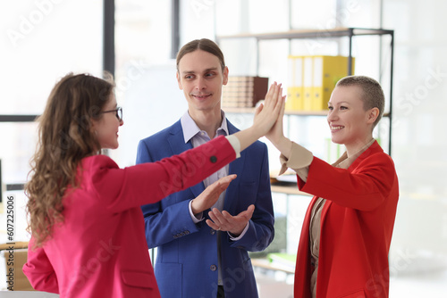 Female colleagues give high five while man boss applauds