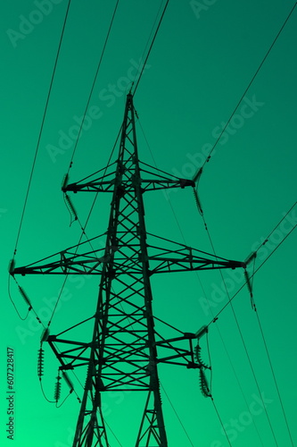 High voltage electric tower silhouette on bright green  background.