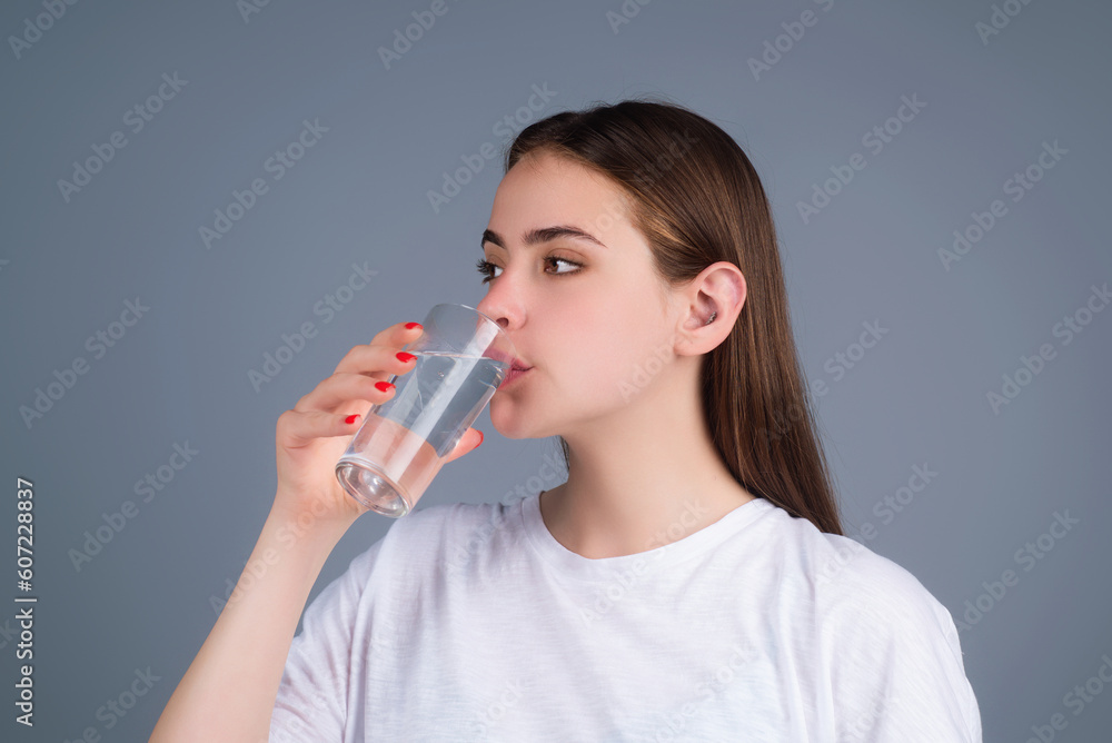 Woman drinking fresh water, isolated on studio background. Female model holds glass of clear water. Health care. Mineral water refreshment, dehydration. Portrait of woman drinking water. Woman drinking fresh water, isolated on studio background. Female model holds glass of clear water. Health care. Mineral water refreshment, dehydration. Portrait of woman drinking water.