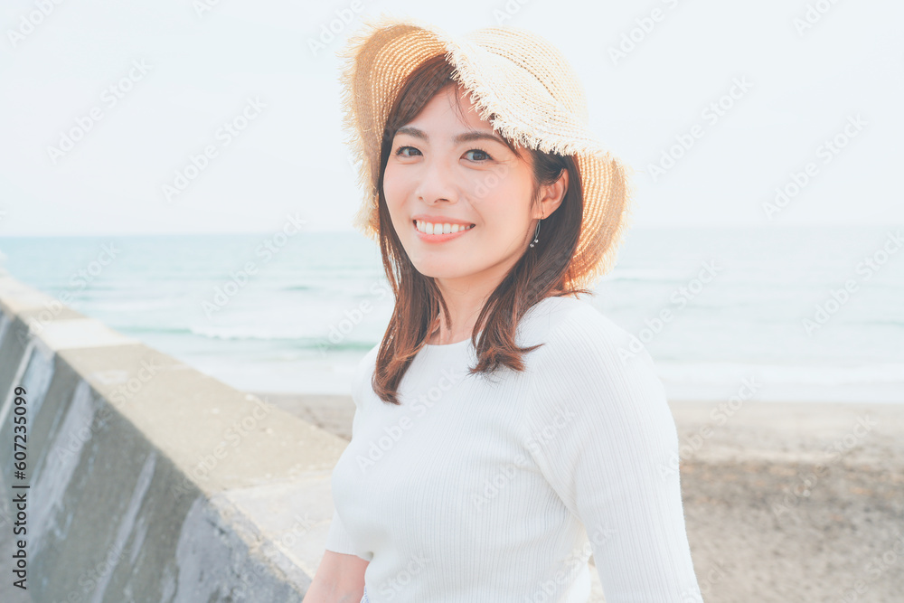 海岸で微笑む麦わら帽子の女性