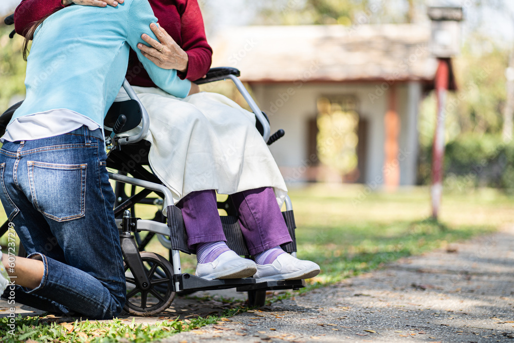 Fototapeta premium Nursing home. Young caregiver helping senior woman in wheelchair.