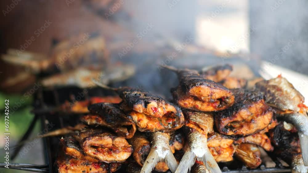 Close-up shot of cooking fish. Baking and roasting marinated fish on barbecue grill. Sea bass or grouper grilled over charcoal. 4K Close-up shot of cooking fish. Baking and roasting marinated fish on barbecue grill. Sea bass or grouper grilled over charcoal. 4K