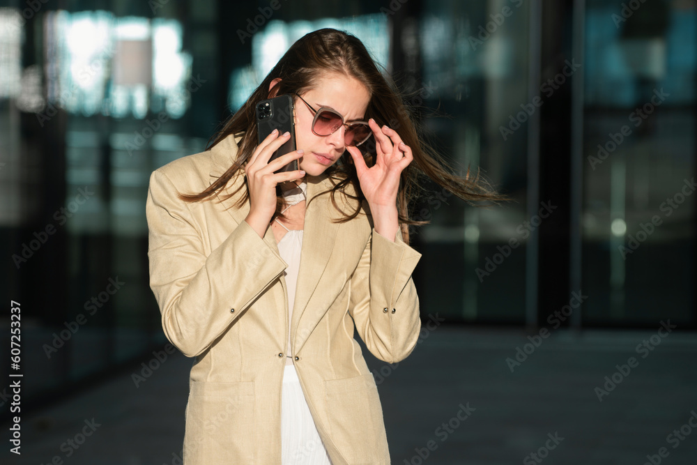 Fashionable business woman talking on phone outdoor on the street, fashion business style. Business woman talking on phone. Business woman in front office. Fashionable business woman talking on phone outdoor on the street, fashion business style. Business woman talking on phone. Business woman in front office.