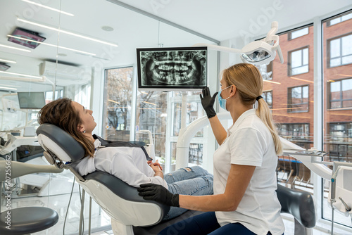Dentist and patient choose treatment during consultation with medical equipment in dentistry.