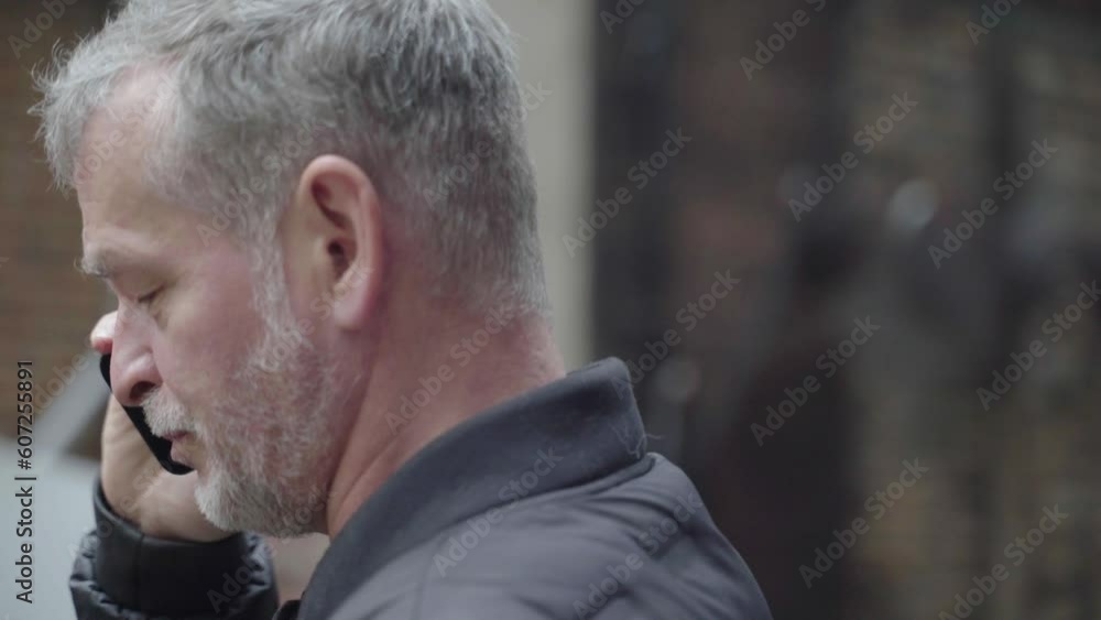 Grey haired man on a phone call talking and ending the conversation Grey haired man on a phone call talking and ending the conversation
