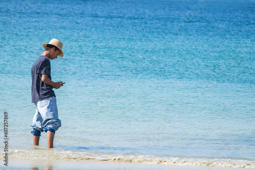 young man walking on the beach and using on the phone
