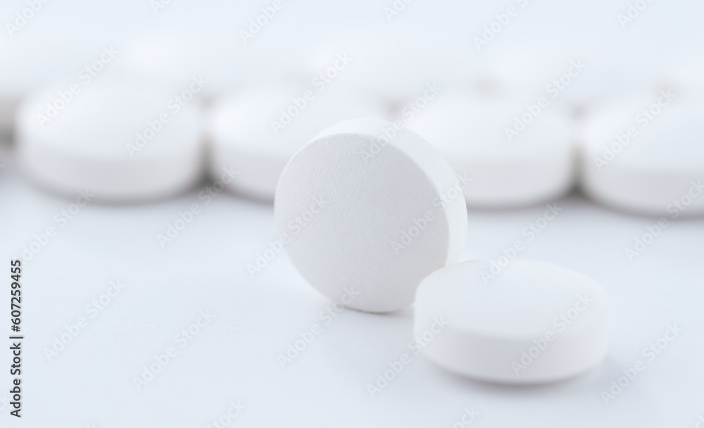 Close-up shot of a round pill against the background of tablets stacked in a row on a production line. Pharmacy medicine pill in production line at medical factory.