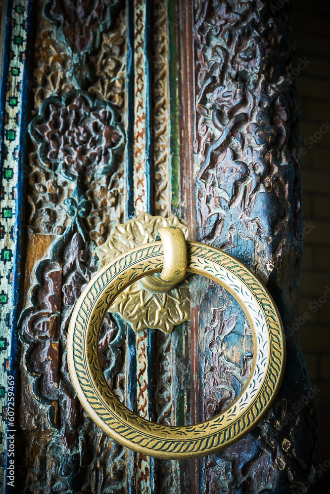 Old wooden carved door with metal door handle in the shape of a ring close- up