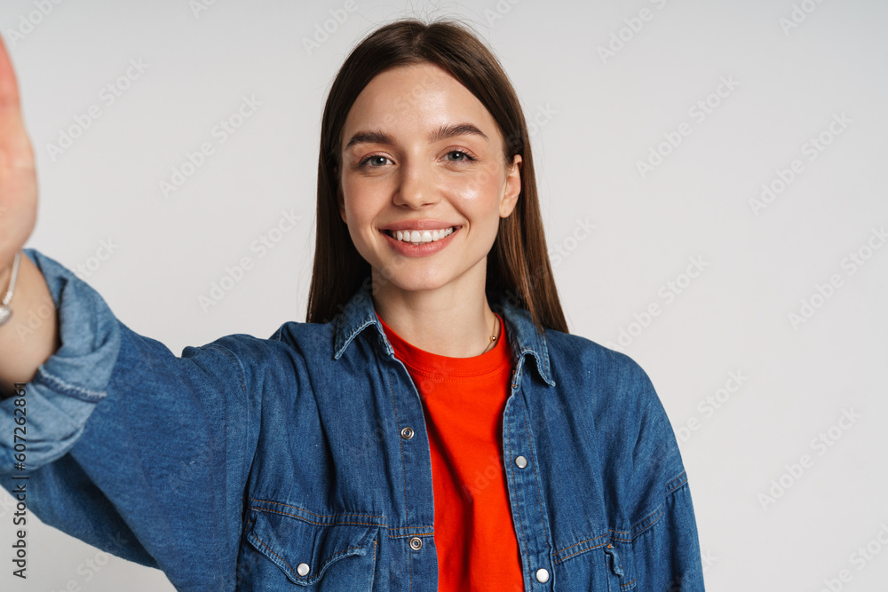 Smiling woman taking selfie isolated over white studio background Smiling woman taking selfie isolated over white studio background