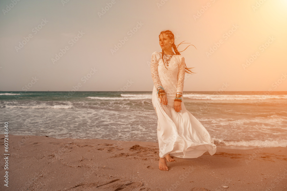 Model in boho style in a white long dress and silver jewelry on the beach. Her hair is braided, and there are many bracelets on her arms. Model in boho style in a white long dress and silver jewelry on the beach. Her hair is braided, and there are many bracelets on her arms.