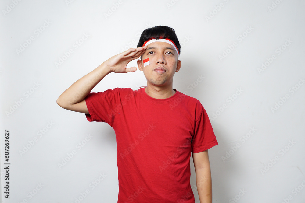 Fototapeta premium Excited young Asian man with attribute Indonesian flag while celebrating Indonesia's independence day