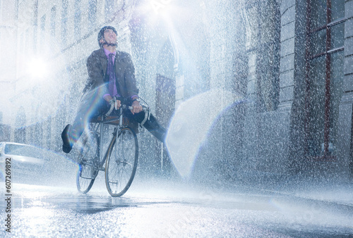 Fototapeta Naklejka Na Ścianę i Meble -  Businessman riding bicycle in rainy street