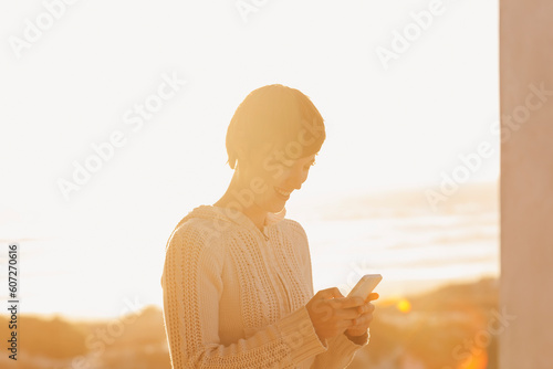Sun shining behind woman using cell phone