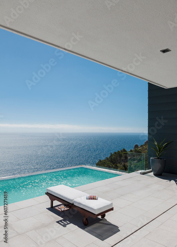 Lounge chair by infinity pool overlooking ocean © KOTO