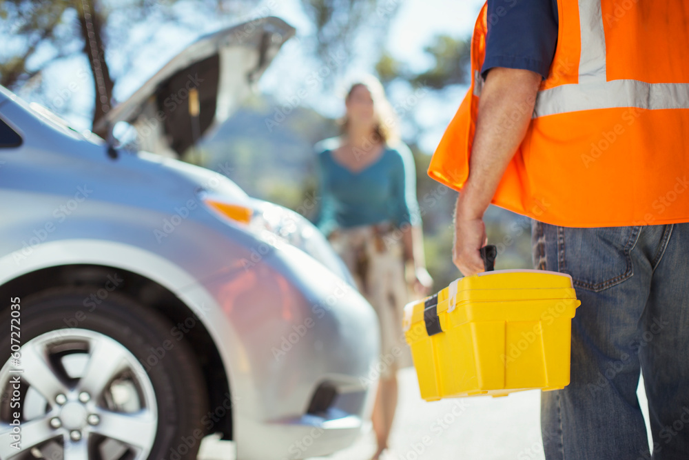 Roadside mechanic with toolbox arriving to help woman Roadside mechanic with toolbox arriving to help woman