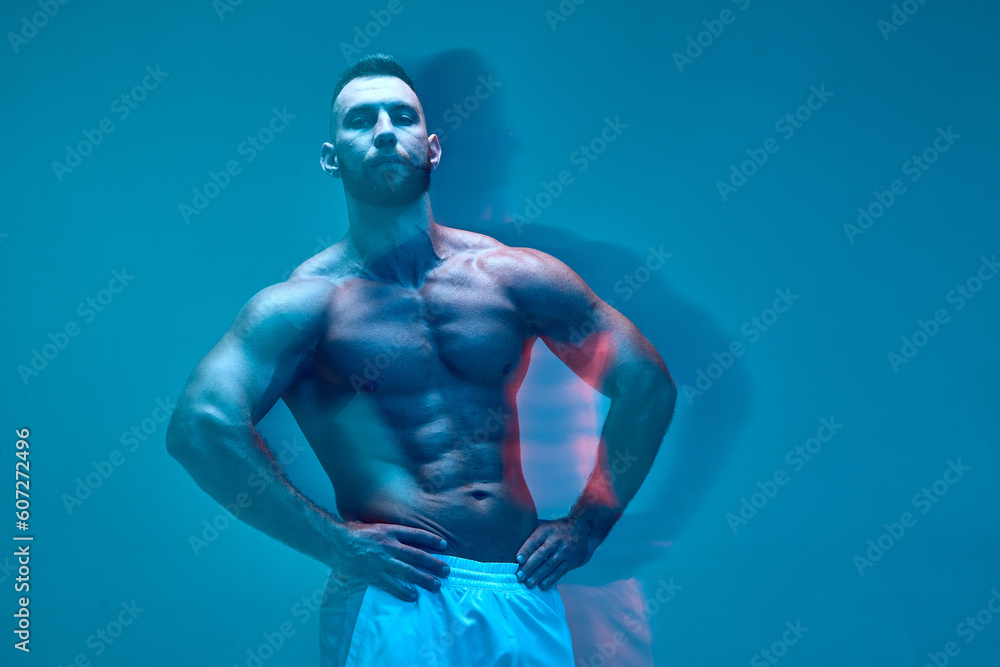 Sportive sexy guy bodybuilder showing naked muscular torso, abdominal and chest muscles. Long exposure. Copy space
